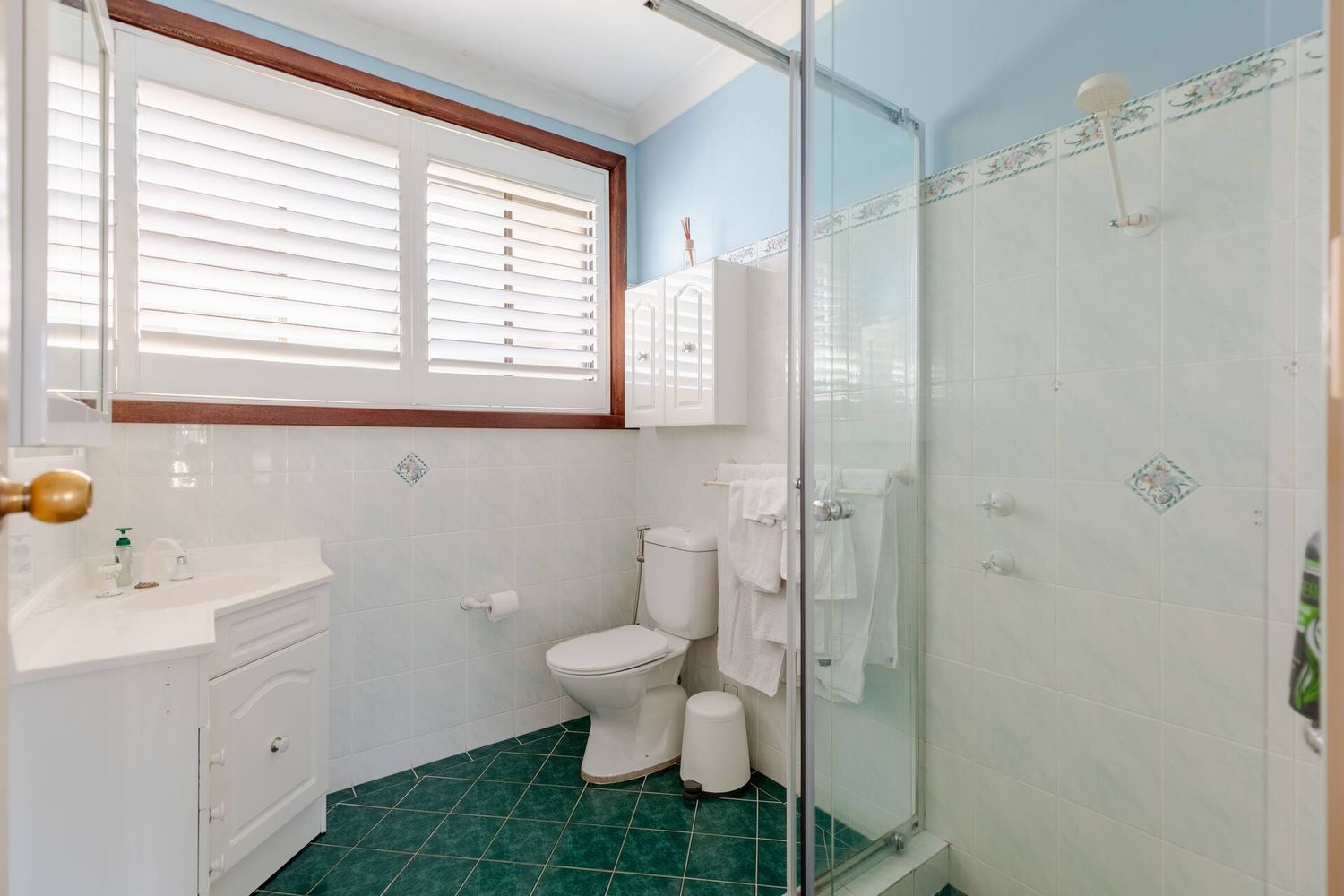 Bathroom with white plantation shutters and a glass shower