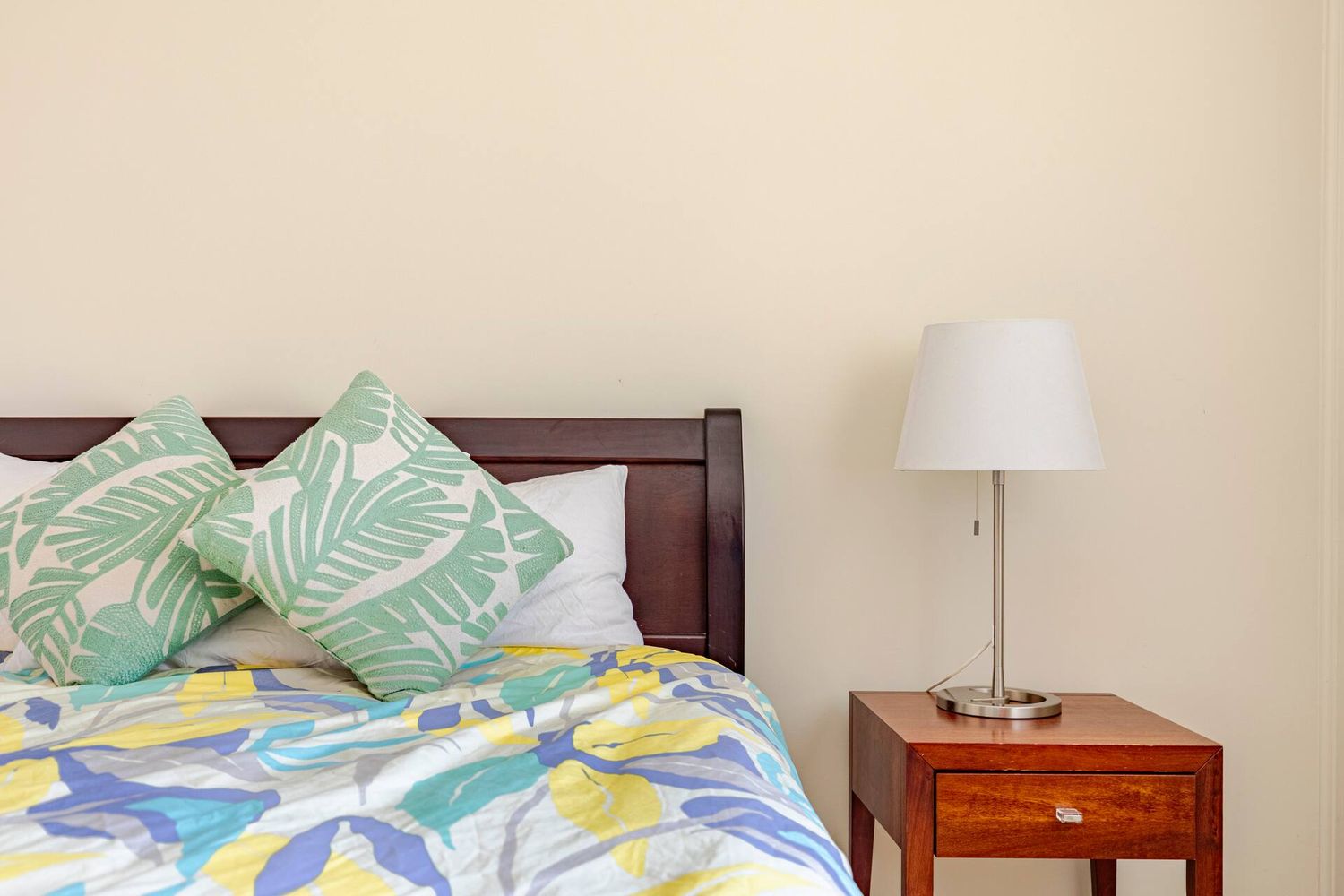 Bedside table and lamp beside a made bed