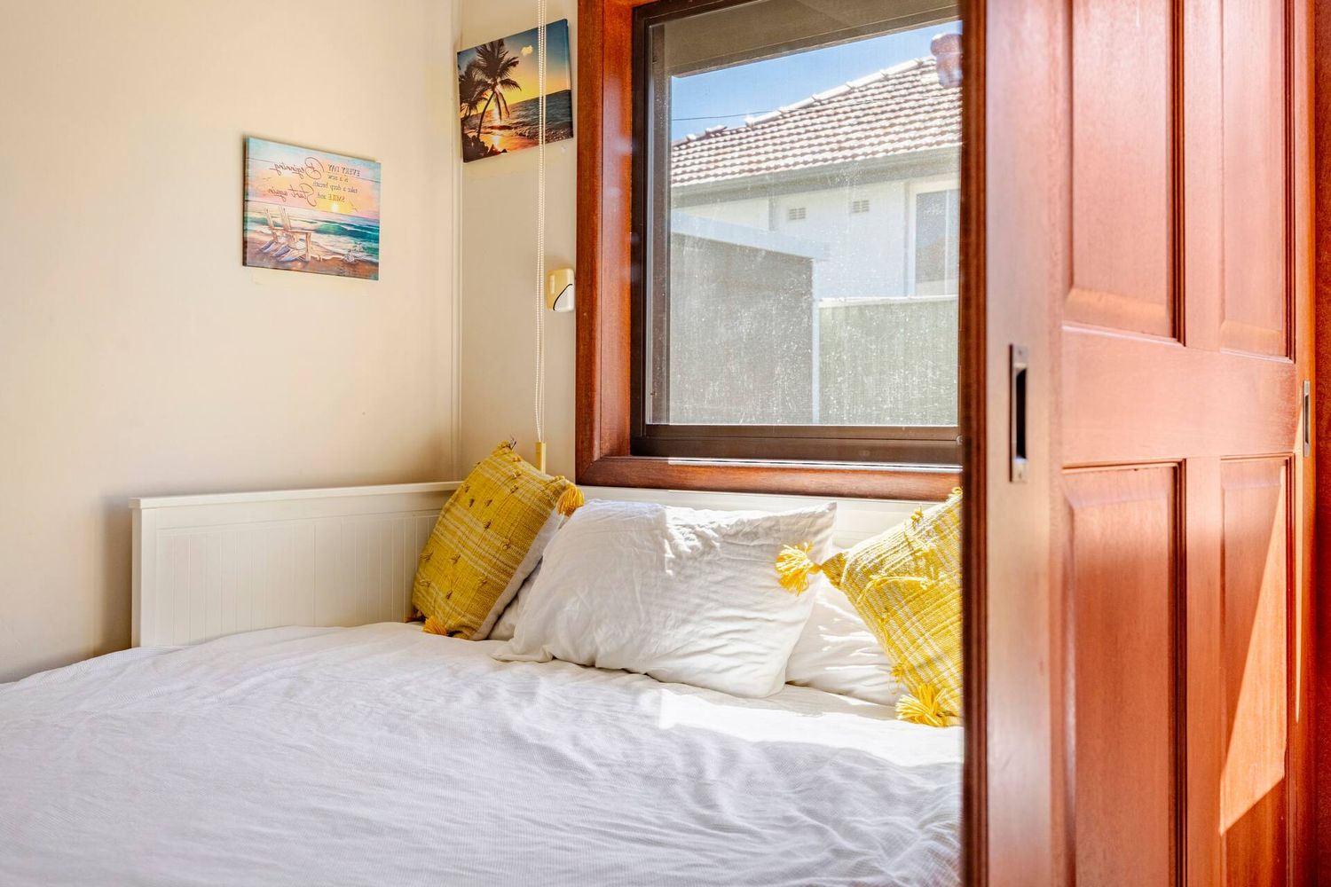 Queen bed beneath a timber-framed window