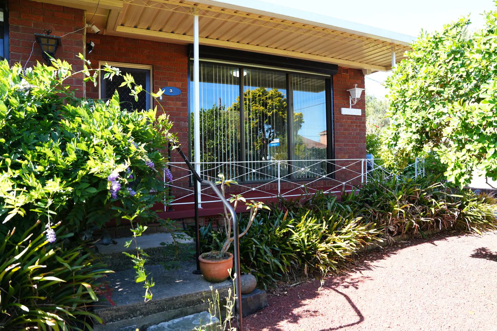 Front of the brick house behind a leafy garden