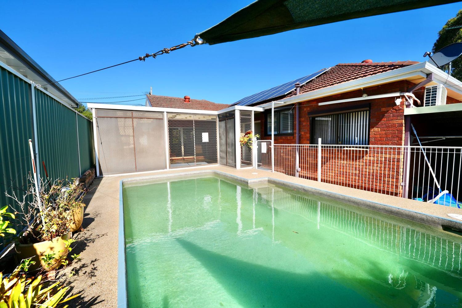 Pool with a shade sail over the paving
